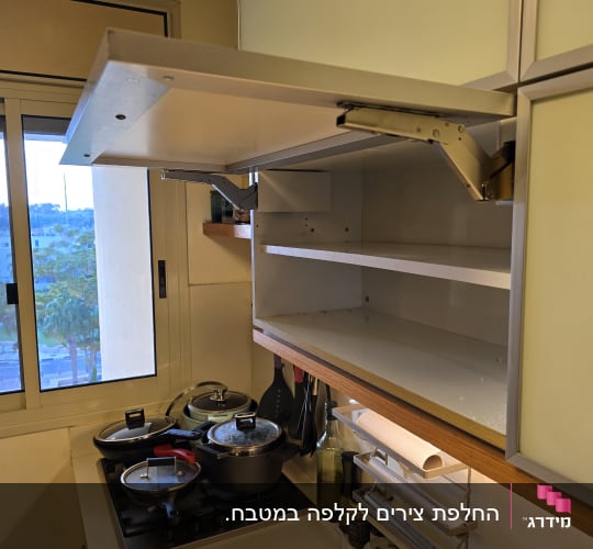 ארונות מטבח פתוחים עם סירים וכלי בישול על הכיריים